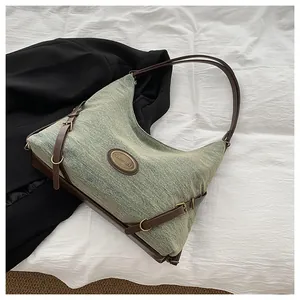 Dettaglio borsa tote in denim con manici in pelle marrone e placca metallica