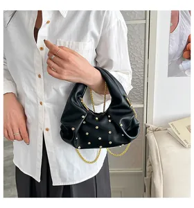 Detailed close-up of a black pleated shoulder bag with gold studs and chain strap