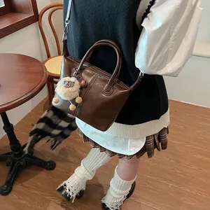 Retro dark brown leather tote bag with a cute sheep charm on a coffee shop background