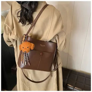 Detail der dunkelbraunen Leder-Eimertasche mit Magnetverschluss und Plüsch-Hundeanhänger