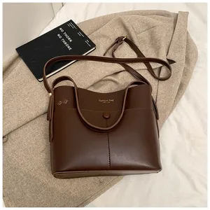 Detaillierte Nahaufnahme der dunkelbraunen matten Eimer-Tasche mit goldener Modeaufschrift