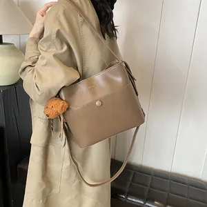 Schicke braune Leder-Eimertasche für Damen mit süßem Bär-Anhänger und modischem Aufdruck