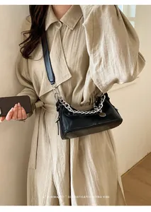 Dettaglio della borsa sottobraccio minimalista in pelle nera con grossa catena in argento