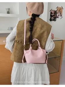 Pale pink bucket bag with knotted handles and adjustable shoulder strap worn by a model
