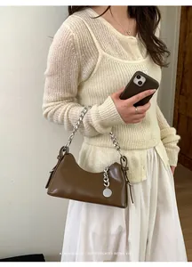 Dettaglio borsa a mezzaluna marrone vintage con catena d'argento su modella
