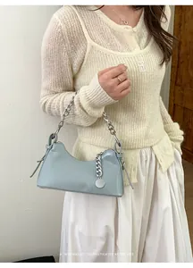 Dettaglio borsa in pelle azzurra con catena d'argento spessa e ciondolo in metallo