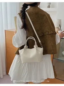 Close-up of cream tote bag with knot handle detail and adjustable shoulder strap