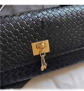 Dettaglio della pelle intrecciata nera e della fibbia quadrata in oro di una borsa chic