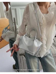 Detail of silver metallic tote bag featuring knotted handles and a sleek crossbody strap