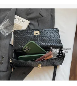 Interno spazioso della borsa a tracolla intrecciata nera con chiusura dorata e oggetti