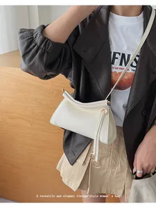 Détail d'un sac bandoulière vintage blanc avec zip à anneau métallique et texture cuir