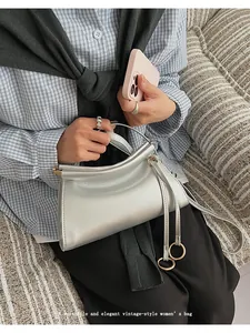 Détail d'un sac à main argenté métallisé avec fermoir en métal et pendentif anneau doré élégant