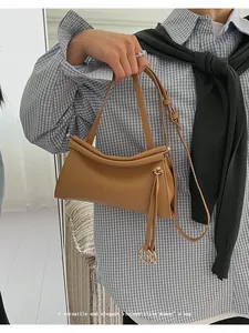 Détail du sac vintage en cuir camel avec bord roulé et franges latérales élégantes