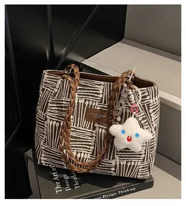 Close-up of canvas tote bag with geometric stripes, leather patch, and star plush charm