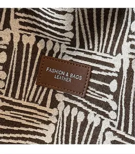 Detail of woven fabric texture and brown leather logo patch on a large tote bag