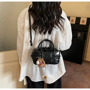 Detail of black glossy Boston handbag featuring a brown horse plush charm on the side