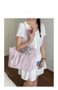 Light purple polka dot tote bag with star and rabbit charms worn on the shoulder