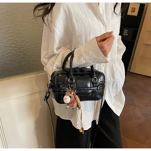 Detail of black glossy leather Boston bag with a cute brown pony plush pendant charm