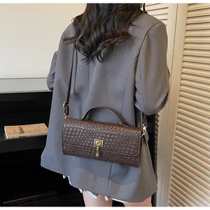 Dettaglio di borsa in pelle marrone con trama a rilievo e chiusura quadrata dorata