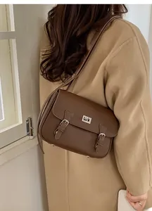 Detail view of dark brown pebbled leather satchel featuring silver buckles and twist lock