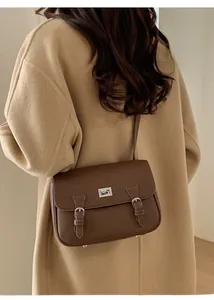 Close-up of brown litchi grain leather crossbody bag with silver lock and buckles