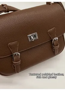 Macro view of brown lychee grain leather handbag with silver metallic twist lock hardware