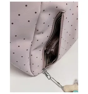 Detail of side zipper pocket on polka dot tote bag with striped lining and metallic puller