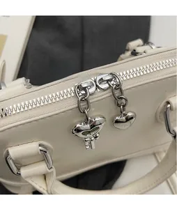 Détail d'un sac en cuir crème avec fermeture éclair en cœur argenté et gravure de clé