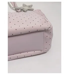 Detail view of the thickened bottom support on a pink polka dot tote bag with star charm