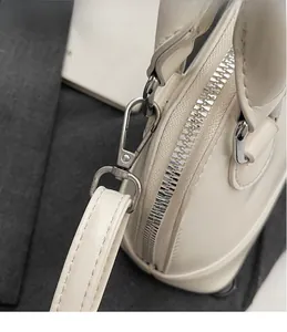 Close-up of premium silver metal hooks and zipper hardware on cream shell bag