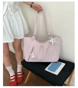 Pink polka dot tote bag detail showing cute star and bunny charms with front zipper pocket.