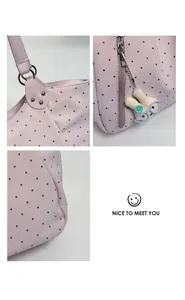 Pink polka dot leather tote bag detail featuring handles, zipper and cute bunny charm.