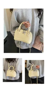 Detail view of cream shell crossbody bag with silver heart key pendant charm