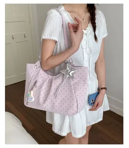 Pink perforated leather hobo bag with star and bunny charms on a model in white lace dress
