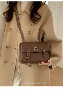 Close-up of dark brown lychee leather crossbody bag with silver twist lock and retro vibe