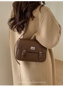 Deep brown pebble leather crossbody bag styled on a camel cashmere coat with a twist lock