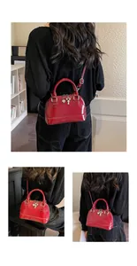 Detail of red patent leather shell bag featuring heart and key charms with strap