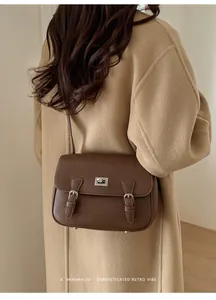 Detail of dark brown leather crossbody bag with silver twist lock and minimalist design
