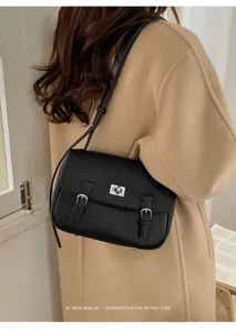 Model wearing black pebble leather satchel bag with silver clasp and adjustable strap