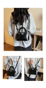 Detail of black shell crossbody bag featuring silver heart charm and adjustable strap