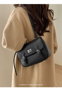 Close-up of black pebble leather handbag with silver metallic turn-lock on wool coat