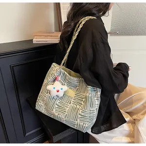 Detail of woven tote bag with green geometric patterns and a plush star pendant accessory
