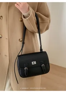 Detail of a black pebbled leather crossbody bag with silver twist lock and retro straps