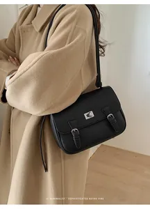 Detail of black pebbled leather texture and silver twist lock on a retro messenger bag