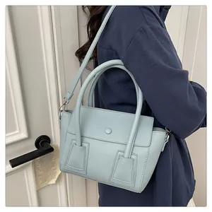 Gros plan sur la texture du cuir grainé bleu clair et les détails latéraux du sac