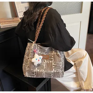 Detail of canvas tote bag with geometric patterns, leather straps and star plush charm