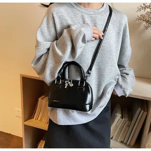 Détail d'un sac à main noir en forme de coquille avec des breloques argentées