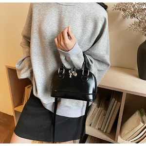 Détail du sac coquillage noir brillant avec breloques cœur et clé argentées élégantes