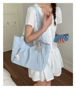 Close-up view of a light blue polka dot tote bag with a cute silver star pendant charm.