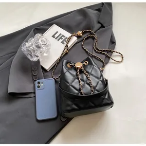 Macro detail of black quilted bucket bag with gold chain strap and drawstring closure